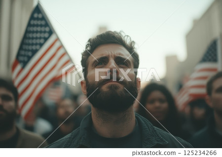 A man with a beard stands in front of a crowd holding an American flag 125234266
