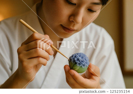 A female Japanese confectioner finishing a nerikiri confection with a hydrangea motif A female Japanese confectioner finishing a nerikiri confection with a hydrangea motif 125235154