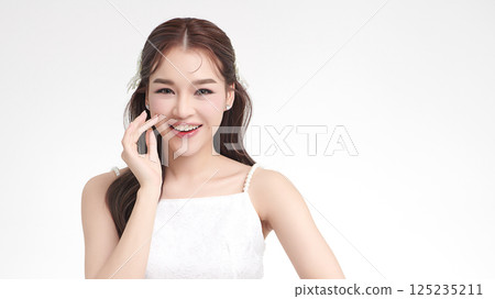 A beautiful young Asian woman with clean, fresh skin against a white background. Skincare, facial treatment, cosmetology, beauty, and spa. An elegant portrait of an Asian woman. 125235211