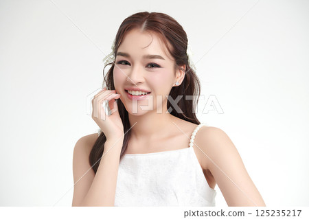 A beautiful young Asian woman with clean, fresh skin against a white background. Skincare, facial treatment, cosmetology, beauty, and spa. An elegant portrait of an Asian woman. 125235217