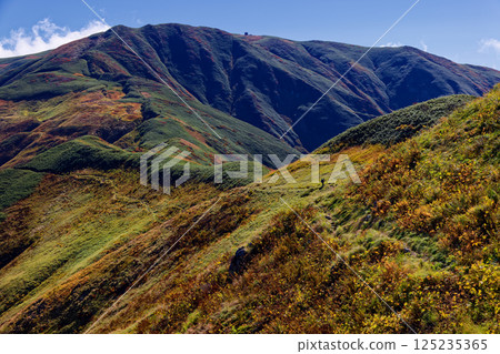 Autumn-colored Iide mountain range, hikers walking along the main ridgeline and Mt. Gonishi 125235365