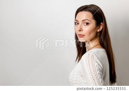 Close-up of a calm, serious, emotionless young woman with brown hair, isolated on a white background. Close-up of a calm, serious, emotionless young woman with brown hair, isolated on a white background. 125235531
