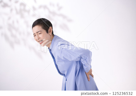 Middle-aged woman grimacing from back pain Middle-aged woman grimacing from back pain 125236532