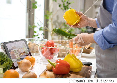 Middle woman cooking while looking at a tablet 125237233