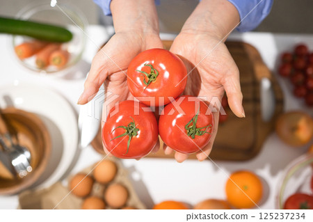 Middle-aged woman's hand holding fresh tomatoes 125237234