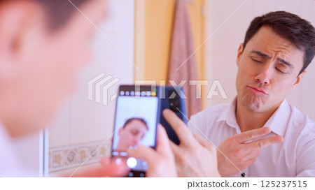 Businessman taking a selfie with a funny expression in bathroom Businessman taking a selfie with a funny expression in bathroom 125237515
