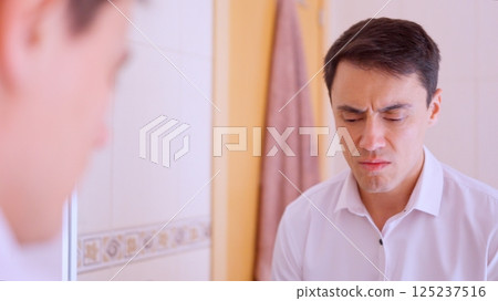 Depressed businessman looking at his reflection in bathroom mirror Depressed businessman looking at his reflection in bathroom mirror 125237516