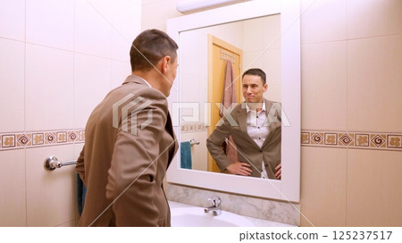 Elegant businessman checking his look in bathroom mirror 125237517