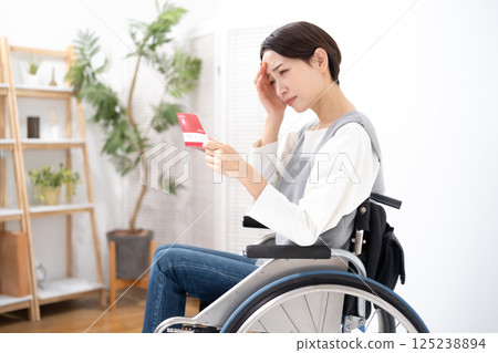 一位坐在輪椅上的女人看到自己的存摺時感到沮喪 一位坐在輪椅上的女人看到自己的存摺時感到沮喪 125238894