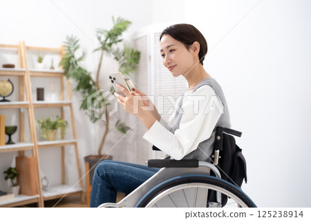 A woman in a wheelchair holding a smartphone and a card A woman in a wheelchair holding a smartphone and a card 125238914