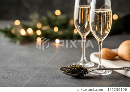 Fine dining elegance captured with caviar in a silver spoon and blurred champagne glasses behind Fine dining elegance captured with caviar in a silver spoon and blurred champagne glasses behind 125239106