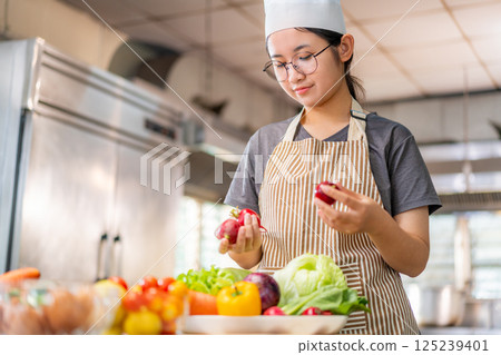Young Female Chef Preparing Fresh Vegetables in Professional Kitchen Young Female Chef Preparing Fresh Vegetables in Professional Kitchen 125239401
