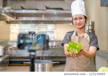 Smiling Female Chef Recording Cooking Video in Kitchen Smiling Female Chef Recording Cooking Video in Kitchen 125239405
