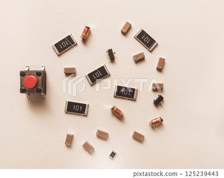 Surface-mount resistors, diodes and push button on white background Surface-mount resistors, diodes and push button on white background 125239443
