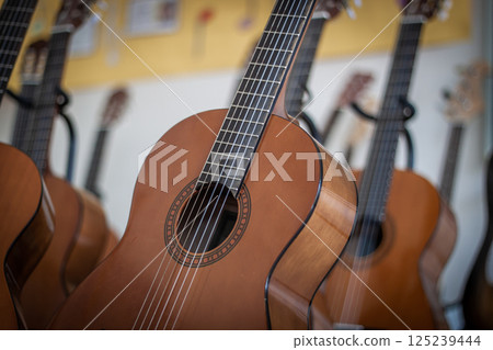 Classical guitars hanging in a music classroom or shop 125239444