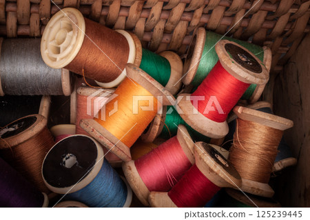 Colorful vintage thread spools in a basket 125239445