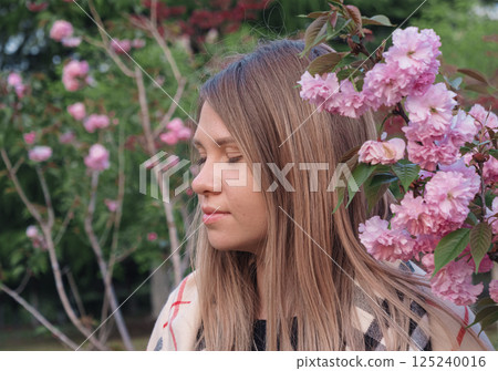 Young woman posing among blooming pink flowers in a botanical garden during springtime Young woman posing among blooming pink flowers in a botanical garden during springtime 125240016