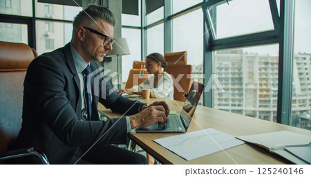 Businesspeople working on laptops in office 125240146