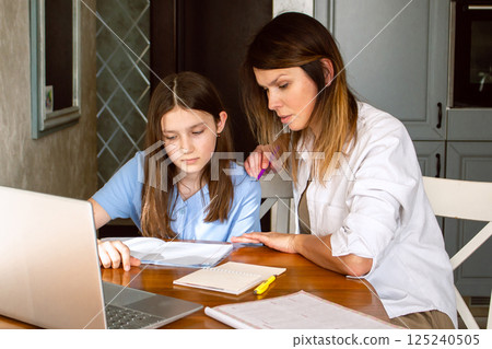 Preteen girl doing homework with mom at home. Mother explaining difficult school subject to her daughter. Spending quality time with child. Happy family. Preteen girl doing homework with mom at home. Mother explaining difficult school subject to her daughter. Spending quality time with child. Happy family. 125240505