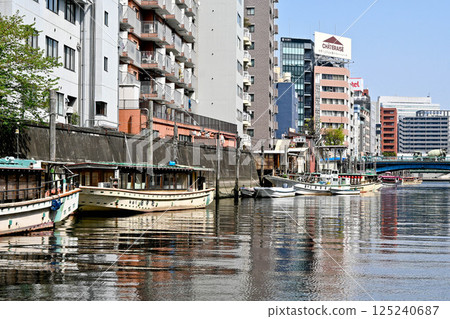 View from a Kanda River cruise ship: Boat lodges and boats on the Kanda River, embankments and crowded buildings 125240687