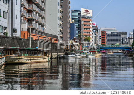 View from a Kanda River cruise ship: Boat lodges and boats on the Kanda River, embankments and crowded buildings 125240688