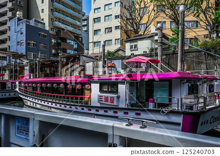 View from a Kanda River cruise ship: Boat lodges and boats on the Kanda River, embankments and crowded buildings View from a Kanda River cruise ship: Boat lodges and boats on the Kanda River, embankments and crowded buildings 125240703