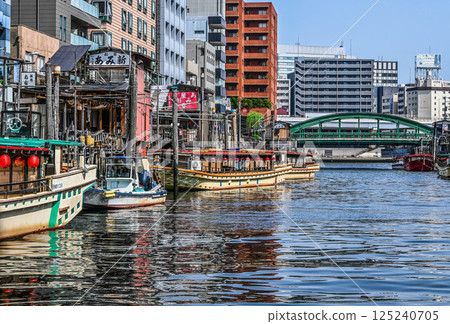 View from a Kanda River cruise ship: Boat lodges and boats on the Kanda River, embankments and crowded buildings 125240705