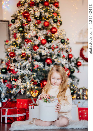 Beautiful little girl with a gift at the Christmas tree.  125242458