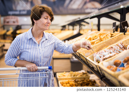 Elderly retired senora buying bread and pastries in grocery section of the supermarket 125243140