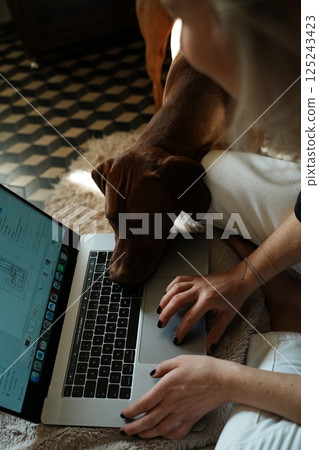 Young woman with her dog working remotely 125243423