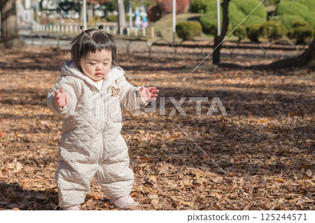 [一歲小孩站在公園裡，在落葉中玩耍] 125244571