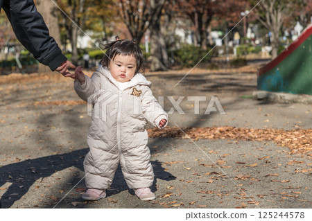 [一名 1 歲的孩子站在落葉覆蓋的冬季公園玩耍] 125244578