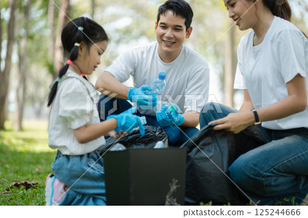 Happy Asian family collecting plastic bottles at the park. Happy Asian family collecting plastic bottles at the park. 125244666