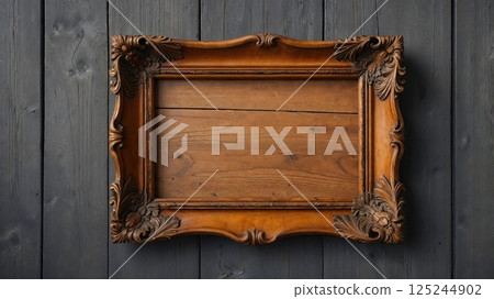 An ornate vintage wooden frame, intricately carved with floral patterns, set against a dark wooden background, evoking a sense of nostalgia and old-world charm, perfect for art displays 125244902