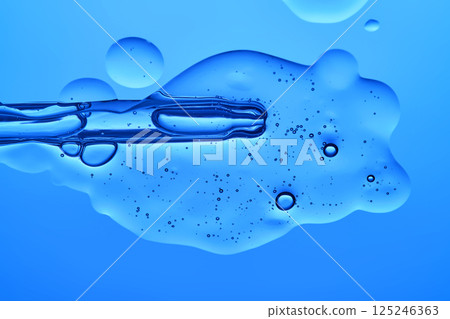 A dropper with a transparent serum texture on a blue background. 125246363