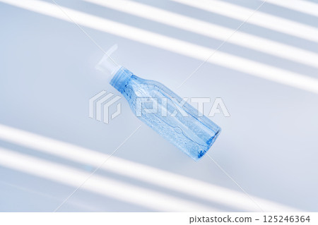 Tube of micellar gel on a white background with stripes of shadows. 125246364