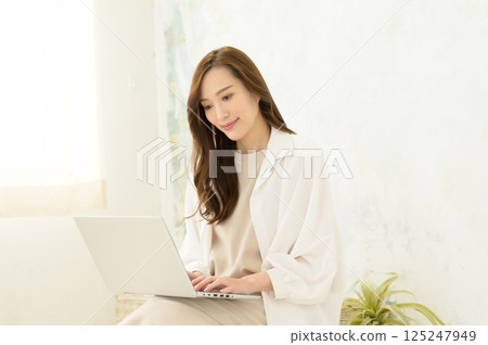 A woman operating a laptop computer on her lap A woman operating a laptop computer on her lap 125247949