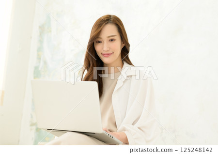 A woman operating a laptop computer on her lap A woman operating a laptop computer on her lap 125248142