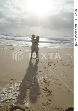 Romantic Couple Embracing on Sunny Beach at Sunset 125248198