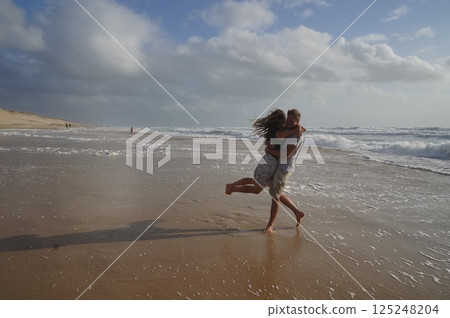 Couple Embracing on Sandy Beach Shoreline Couple Embracing on Sandy Beach Shoreline 125248204