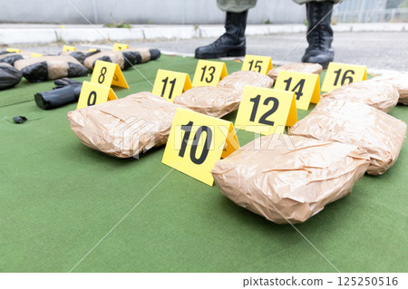 Police officer standing guard over seized packages of drug Police officer standing guard over seized packages of drug 125250516