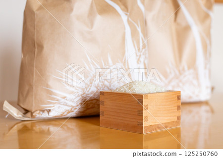 Rice bags and rice in a measuring box on a table Rice bags and rice in a measuring box on a table 125250760