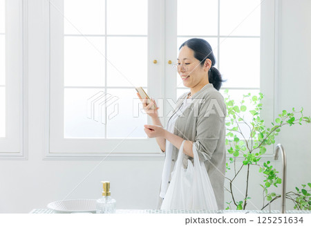 Woman looking at smartphone, housewife Woman looking at smartphone, housewife 125251634