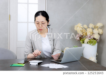 Housewife worried about receipts in household account book 125251643