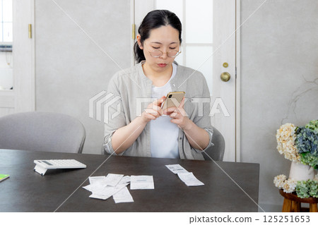 微笑的女人拿著智慧型手機,家庭會計應用程序 微笑的女人拿著智慧型手機,家庭會計應用程序 125251653