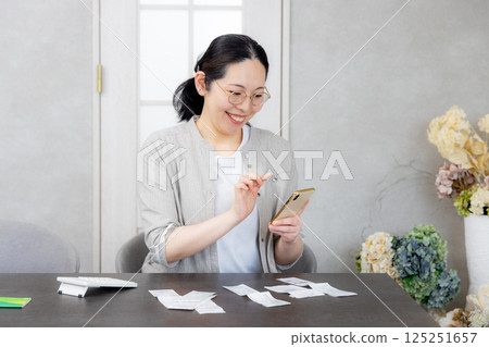 Smiling woman holding a smartphone, household accounting app Smiling woman holding a smartphone, household accounting app 125251657