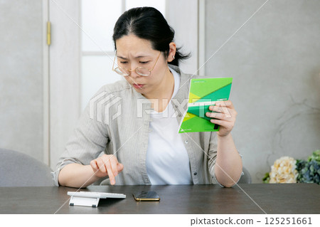 一位中年婦女看著她的存摺，擔心 125251661