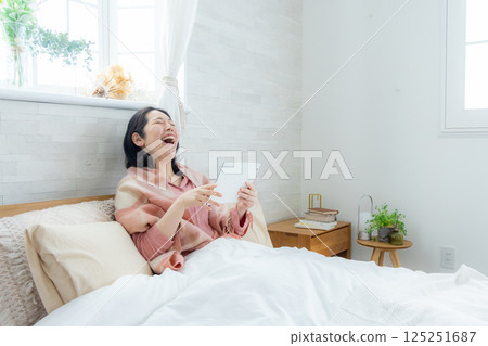 A woman watching a tablet in bed A woman watching a tablet in bed 125251687