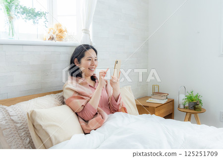 一名婦女在床上的看一個智能手機 125251709