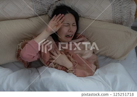A woman holding her head due to poor health 125251718